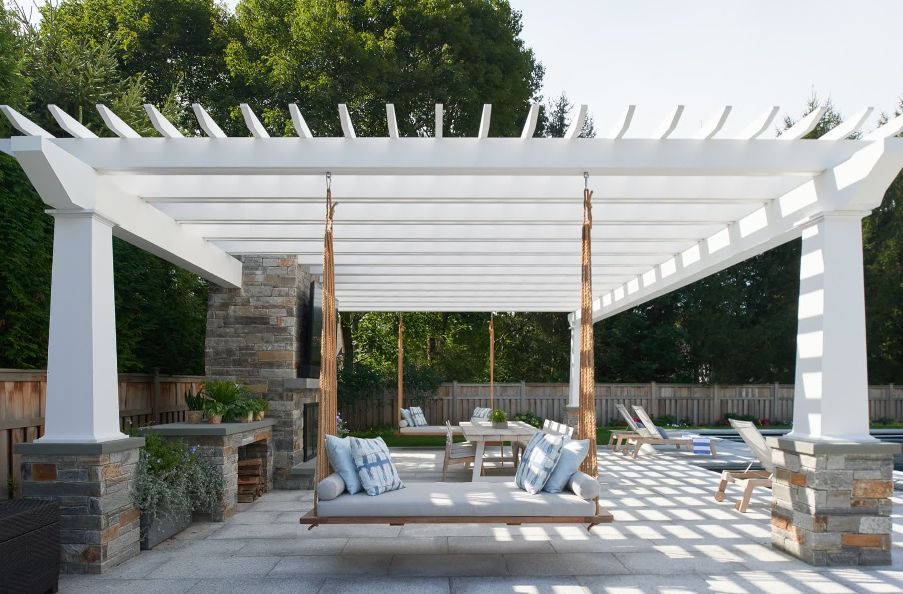 White pergola and hanging daybed at a Lorono home
